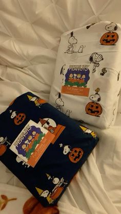 two pieces of clothing sitting on top of a bed covered in white sheets and pumpkins