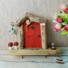 a red door with an owl figurine on it and flowers in the background