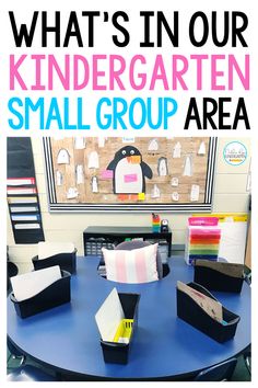 a blue table topped with lots of books and folders next to a penguin bulletin board