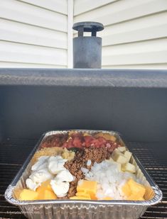 an aluminum pan filled with food on top of a grill next to a house door