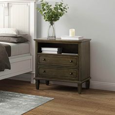 a bedroom with a bed, nightstand and plant on the end table in front of it