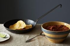 a table topped with bowls filled with food next to a bowl of chips and a plate of guacamole