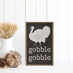 a wooden sign that says gobble gobble with a turkey on it next to some dried wheat