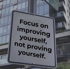 a white sign that says focus on imppoing yourself, not providing yourself in front of some tall buildings