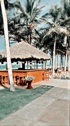 a tiki bar with palm trees and the ocean in the backgrouds