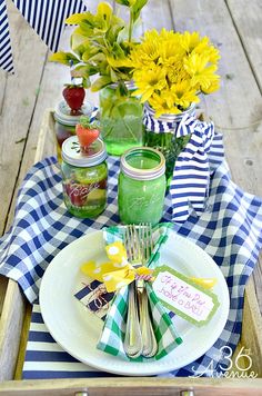 a picnic table set with mason jars, flowers and napkins on top of it