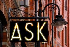 a neon sign that says ask on the side of a building