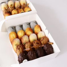 two boxes filled with assorted pastries on top of a white table next to each other