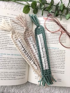 an open book with glasses on top of it next to some yarn and reading material