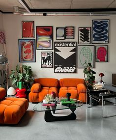 a living room filled with orange couches and pictures on the wall above them,