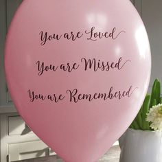 a white balloon with the words you are loved, you are missed, you're remembrance written on it