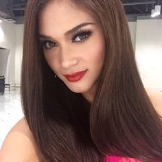 a woman with long brown hair and red lipstick posing for a photo in an empty room