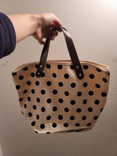 a person holding a polka dot bag in their hand with the handle extended to show it's interior