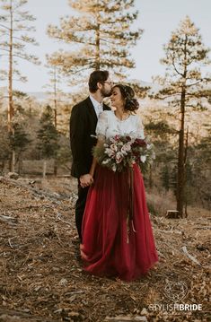 a bride and groom are standing in the woods holding each other's foreheads