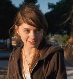 a young woman standing on the side of a road with her hair blowing in the wind