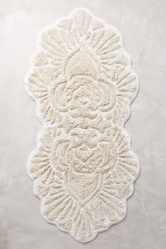 a white rug with an intricate design on the bottom and sides, in front of a white background