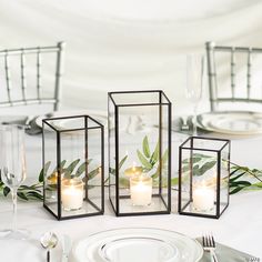 candles are lit in glass cubes on the table set for an elegant wedding reception