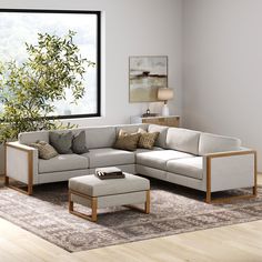 a living room with a sectional couch and footstool next to a large window