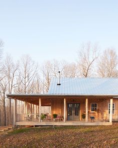 a small wooden cabin in the woods with a porch and covered veranda area on one side