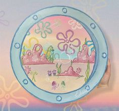 a hand holding a paper plate with an image of flowers and sea animals on it