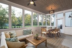 a large screened porch with seating and tables on the side, facing an open field