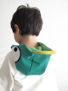 a young boy wearing a green and yellow neck gaiter with a bird on it