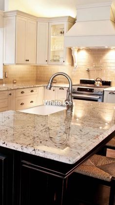 a large kitchen with marble counter tops and white cabinets