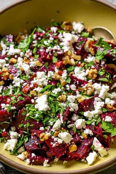 beet salad with feta cheese and walnuts in a yellow bowl on a table