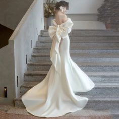 a woman in a white dress is walking down the stairs with her back to the camera