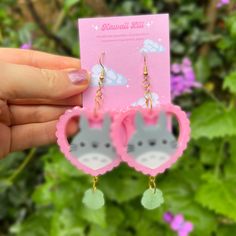 a pair of pink earrings with grey cats on them