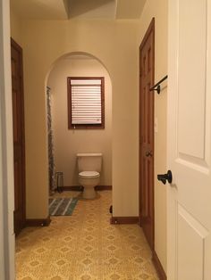 an archway leads to a bathroom with a toilet in the corner and a rug on the floor