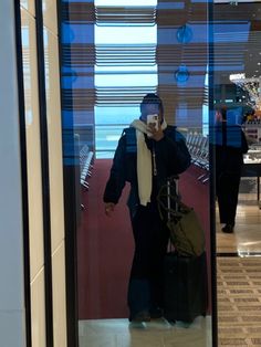 a man taking a selfie with his cell phone in front of an airport lobby