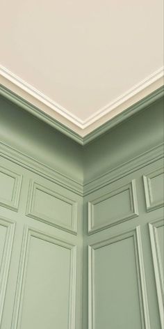 the corner of a room with green walls and white trim on the ceiling is shown