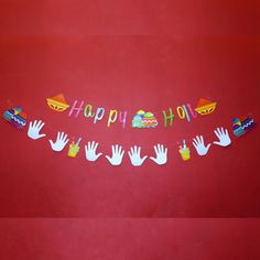 a happy birthday banner with hands and food on it hanging from a line in front of a red wall