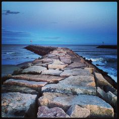 the rocks are lined up along the water's edge as the sky is blue