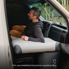 a man sitting in the back of a white van with pillows on it's seat