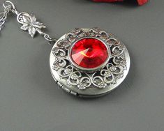 Ruby red Victorian Steampunk Locket is 30 inches long. Feminine antique silver locket is decorated with Victorian style antique silver floral frame. I have set Swarovski red Crystal stone in the middle of locket which is set in silver setting. Pendant is hanging from a antique silver leafy rosary link. Necklace is finished with antique silver chain and antique silver royal toggle clasp. Locket is 32 mm in size. It opens and has room for two photos inside. Please note: I DO NOT DO ENGRAVING OR IN Ruby Birthstone, Silver Locket, Victorian Steampunk, Floral Frame, Silver Lockets, Red Crystals, Brides And Bridesmaids, Crystal Stone, Toggle Clasp