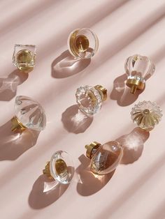 an assortment of glass knobs sitting on top of a pink surface with shadows coming from them