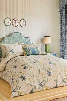 a bed sitting in a bedroom next to a window covered in blue and white curtains