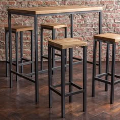 four stools and a table in front of a brick wall with wood flooring