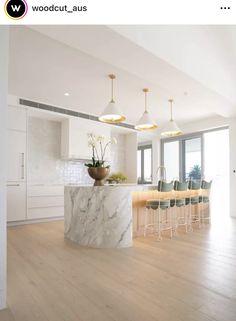 a large kitchen with marble counter tops and bar stools in the middle of it