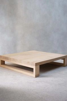 a wooden coffee table sitting on top of a white carpeted floor next to a gray wall