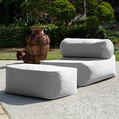 two green and white cushions sitting on top of a cement slab next to a vase