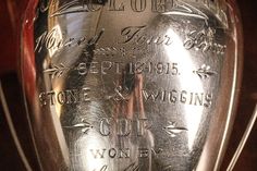 a silver trophy sitting on top of a table next to a wooden wall with writing all over it