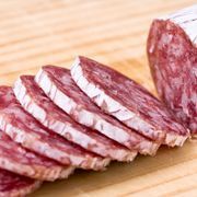 slices of salami sitting on top of a wooden cutting board