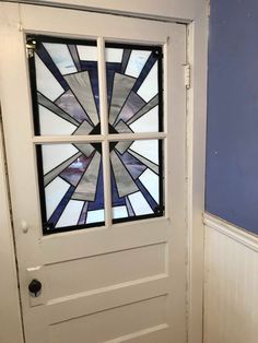 a white door with a stained glass window on it's side and blue walls