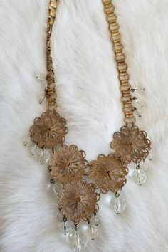 "This is a vintage 1920s-1930s statement necklace. The gold tone metalwork is very intricate and is in a round filigree design. There is one visible area of tarnish (pictured) from wear and age. The necklace has a unique chain and crystal tone details. All of the crystal tone gems are in excellent condition. Overall this necklace is in great condition. Measurements: Length: 9.5\" | Length of detail: 2.5\" Unless otherwise stated all vintage items are used and may have minor to moderate wear or d Gold Medallion Jewelry For Vintage Events, Gold Costume Jewelry Necklace For Vintage Events, Ornate Necklace With Intricate Design For Vintage Events, Victorian Filigree Necklaces For Vintage Events, Victorian Filigree Necklace For Vintage Events, Ornate Gold Necklaces For Vintage Events, Ornate Brass Necklaces For Wedding, Ornate Gold-tone Metal Jewelry, Vintage Filigree Medallion Necklace