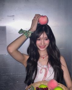 a woman holding a basket with fruit on top of her head and an apple above her head