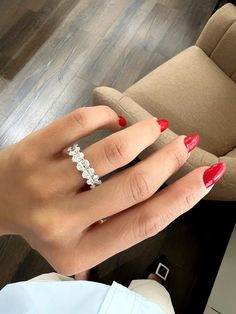 a woman's hand with red nail polish on it and a diamond ring in the middle