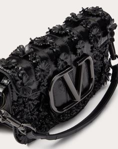 Valentino Garavani Locò small shoulder bag in eel skin with flower appliqué and metallic VLogo Signature detail. Equipped with both a detachable sliding chain and a detachable handle, this accessory can be worn as a crossbody/shoulder bag or carried as a handbag. - Tone-on-tone hardware - Magnetic closure - Removable leather handle - Shoulder strap with removable sliding chain - Suede leather lining. Interior: one slip pocket Shoulder strap drop length: min. 33 cm to max. 55 cm / min. 13.0 in. t Embroidered Shoulder Bag, Valentino Garavani Bag, Studded Sneakers, Oxford Boots, Wedge Loafers, Embroidered Bag, Iconic Bags, Shoulder Bag Black, Demi Fine Jewelry